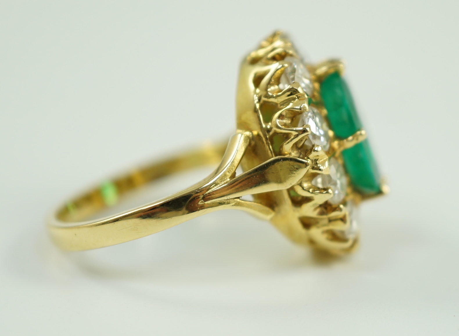 A modern 18ct gold, emerald and diamond set oval cluster ring